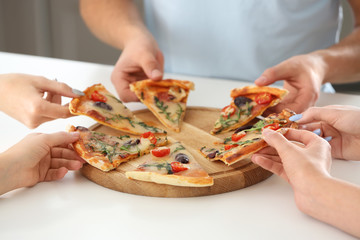 Young people sharing tasty pizza at table, closeup