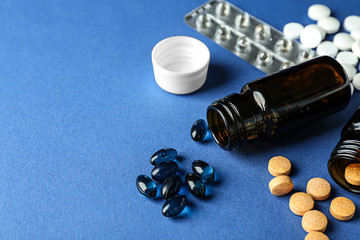Glass bottles with pills on color background