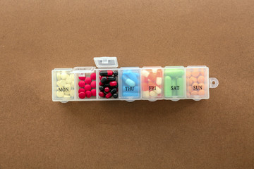 Plastic container with different pills on color background