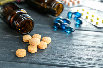 Glass bottles with pills on wooden table