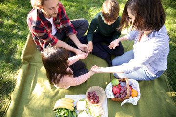 Family praying before meal in park