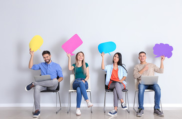 Young people with blank speech bubbles sitting near white wall