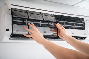 Electrician repairing air conditioner indoors