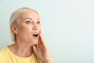 Portrait of emotional mature woman on light background