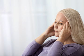 Portrait of mature woman suffering from headache at home