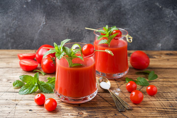 Tomato juice with mint in glass and fresh tomatoes on a wooden table. Healthy organic food concept