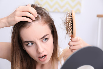 Woman with hair loss problem looking in mirror