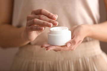 Fototapeta na wymiar Young woman holding jar of cream, closeup