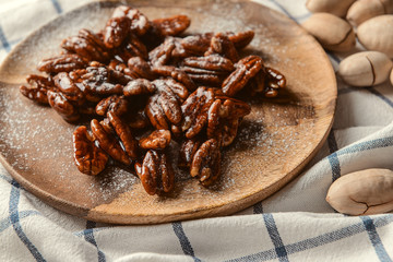 Plate with candied pecan nuts on table