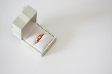  gift box with a bow and a wedding ring inside stands on a white background