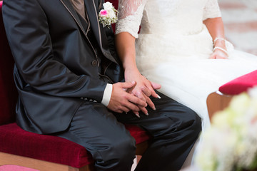 Hochzeitspaar sitzt händchen haltend in der Kirche 