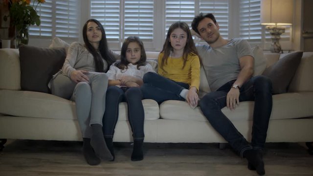 Father, Mother and daughters Watching TV in Their Cozy Living Room