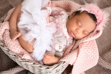 Cute African-American baby sleeping in wicker basket