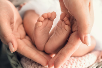 Obraz na płótnie Canvas Mother's hands holding tiny feet of little baby, closeup