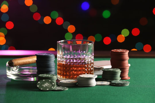 Chips, glass of whiskey and cigar on table in casino