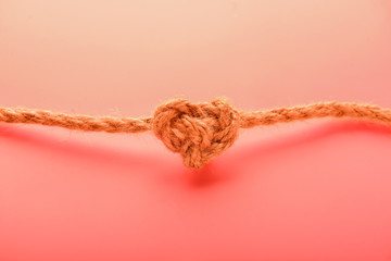 Rope with knot on coral background