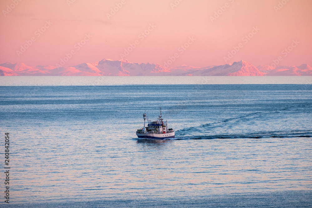 Wall mural Fishing boat cruising on arctic sea to fish at sunset in winter