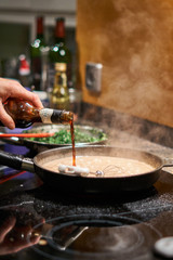 Kochender Soße wird Wein beigefügt