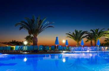 Swimming pool and palm trees at the evening time