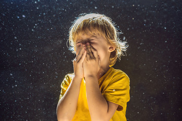 Allergy to dust. Boy sneezes because he is allergic to dust. Dust flies in the air backlit by light