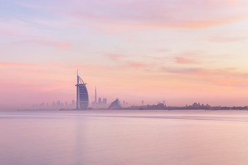 Stunning view of Dubai skyline from Jumeirah beach to Downtown lighted with warm pastel sunrise colors. Dubai, UAE.