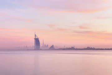 Zelfklevend Fotobehang Stunning view of Dubai skyline from Jumeirah beach to Downtown lighted with warm pastel sunrise colors. Dubai, UAE. © Kertu