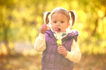 Little girl child enjoying playing with soap bubbles in autumn park