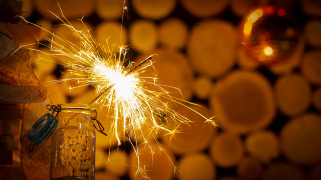 Rustic wooden wall with a sparkler and golden bokeh Christmas concept