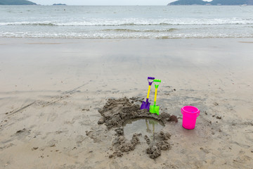 Fototapeta na wymiar toy shovels and bucket with a hole on a beach