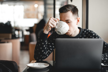 Young guy doing distant work in a cafe