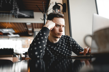 A freelancer or journalist frowns at a laptop. Has difficulty completing a job or order