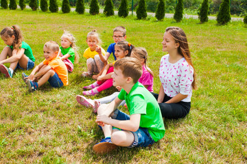 Smiling children sitting on a grass at outdoor lesson