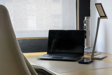 Despacho con sillón y portátil con fondo blanco y luz natural