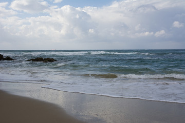Waves crashing on shoreline with moody dramatic sky