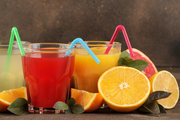 Citrus juices. Lemon, grapefruit and orange juice with fresh fruits on a brown wooden table