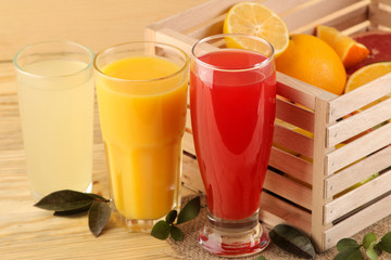 Citrus juices. orange, lemon and grapefruit juice with fresh fruits in a box on a natural wooden background