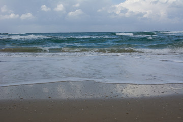 Waves crashing on shoreline with moody dramatic sky