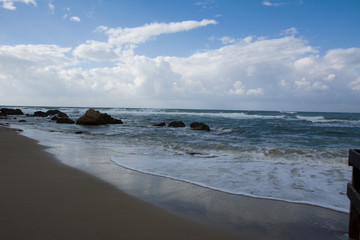 Fototapeta na wymiar Waves crashing on shoreline with moody dramatic sky