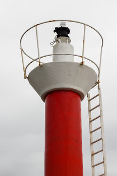 Faro rojo y blanco con luz roja de entrada a puerto