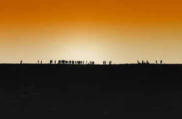 A large group of young people gathered outdoors at sunset