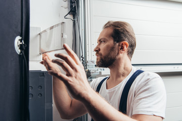 Fototapeta premium concentrated male bearded handyman checking electrical box