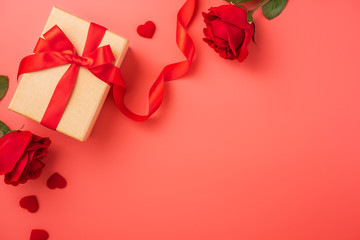 Gift box with red ribbon and rose in trendy colour of 2019 living coral, concept of Valentine's, anniversary, mother's day, copy space, top view.