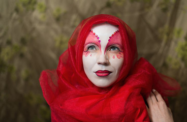 Mysterious mystical woman with a face painted white-red.