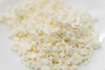 Cottage cheese in a plate on a wooden background.