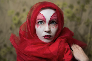 Mysterious mystical woman with a face painted white-red.