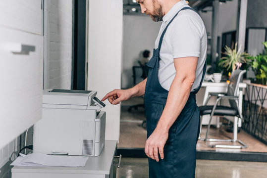 cropped image of male handyman repairing copy machine in modern office