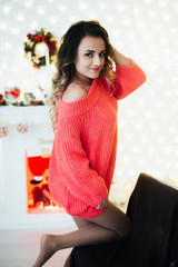 Girl in a Pink wool sweater on the background of the fireplace garlands and Christmas trees