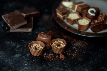 different, sweet pralines of dark, milk and white chocolate on a dark, wooden background
