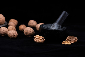 Walnut concept photo, walnuts with mortar and pestle on black background