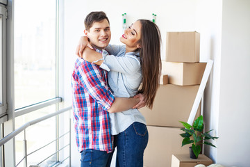 New Home. Funny young couple enjoy and celebrating moving to new home. Happy couple at empty room of new home